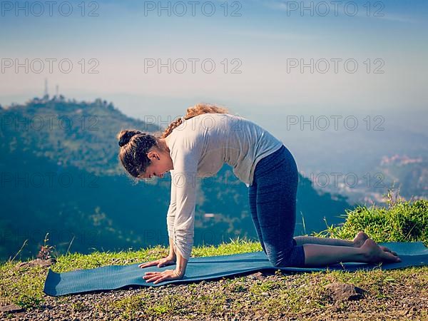 Vintage retro effect hipster style image of sporty fit woman practices yoga asana Marjariasana