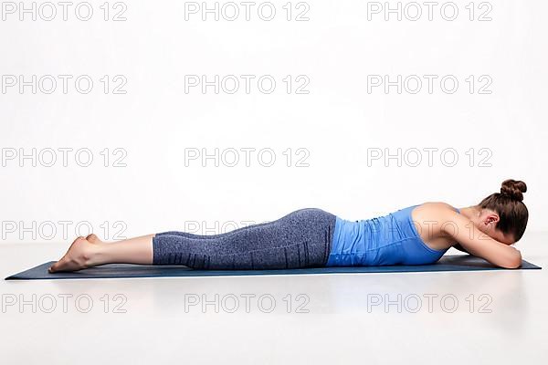 Sporty woman relaxes in yoga asana Makarasana
