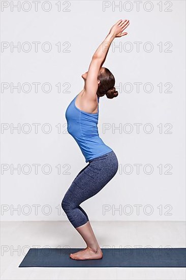 Sporty fit woman doing Surya Namaskar ashtanga vinyasa yoga asana Utkatasana