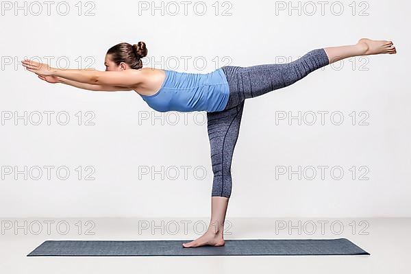 Beautiful sporty fit woman practices yoga asana Virabhadrasana 3