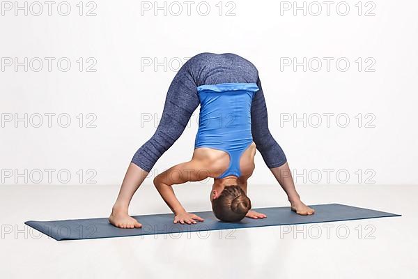 Beautiful sporty fit woman practices Ashtanga Vinyasa yoga asana Prasarita padottanasana B