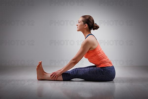 Sporty fit woman practices Ashtanga Vinyasa yoga back bending asana Paschimottanasana