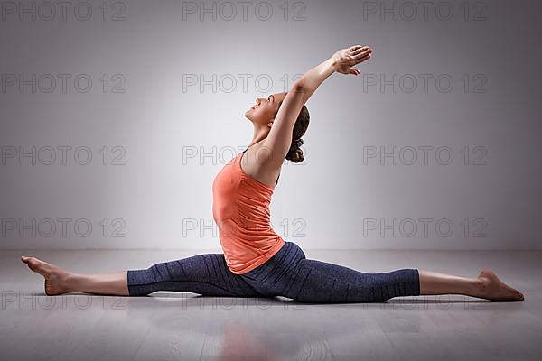 Sporty fit woman doing Hatha yoga asana Hanumanasana