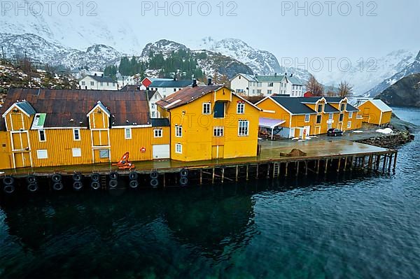 Panorama of Nusfjord authentic fishing village with yellow rorbu houses in Norwegian fjord in winter. Lofoten islands