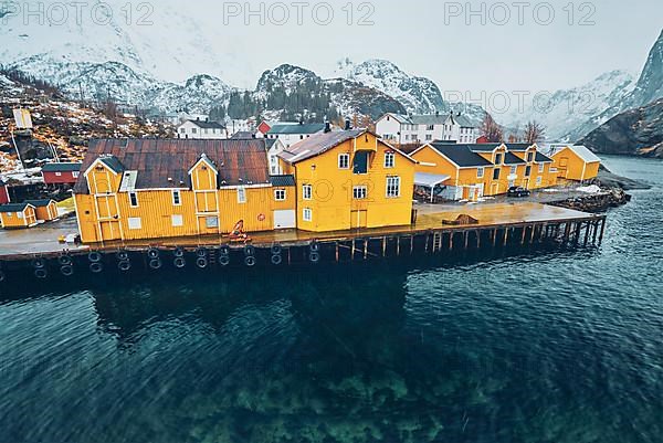 Panorama of Nusfjord authentic fishing village with yellow rorbu houses in Norwegian fjord in winter. Lofoten islands