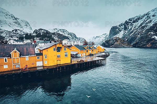 Panorama of Nusfjord authentic fishing village with yellow rorbu houses in Norwegian fjord in winter. Lofoten islands