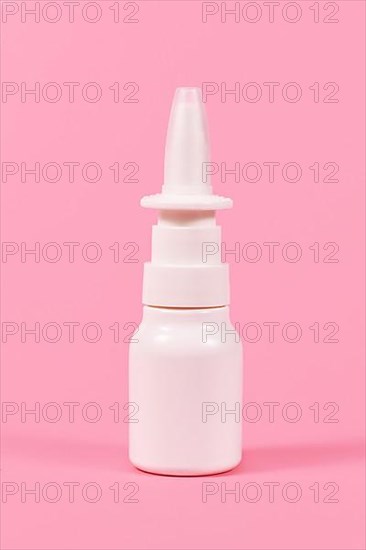 White nasal spray bottle on pink background