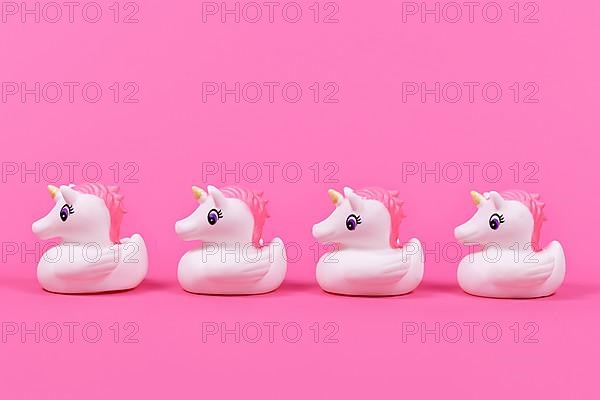 Four cute rubber duck unicorn in a row on pink background