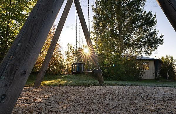 Children's swing with sun star at sunset