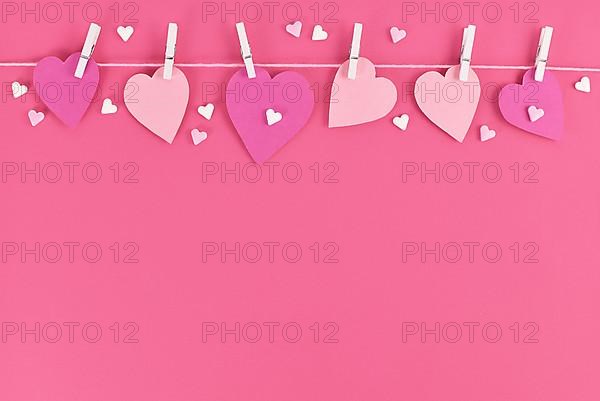 Pink paper hearts hanging from line with pegs and sugar sprinkles