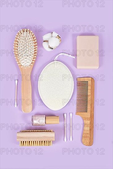 Eco friendly wooden beauty and hygiene products like comb and soap arranged on violet background