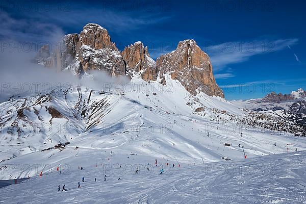 View of a ski resort piste with people skiing in Dolomites in Italy