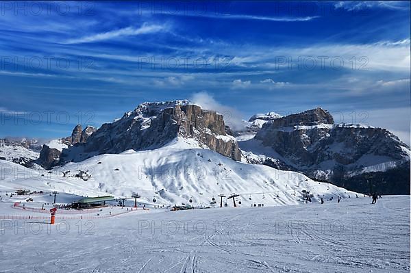 View of a ski resort piste with people skiing in Dolomites in Italy