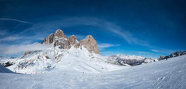 Panoramaof a ski resort piste with people skiing in Dolomites in Italy