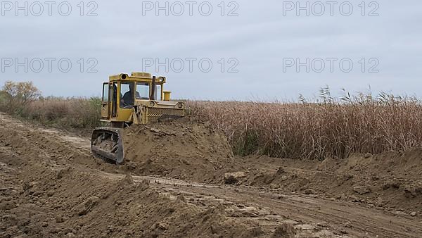 Bulldozer removes dam in the delta Danube river. Close up