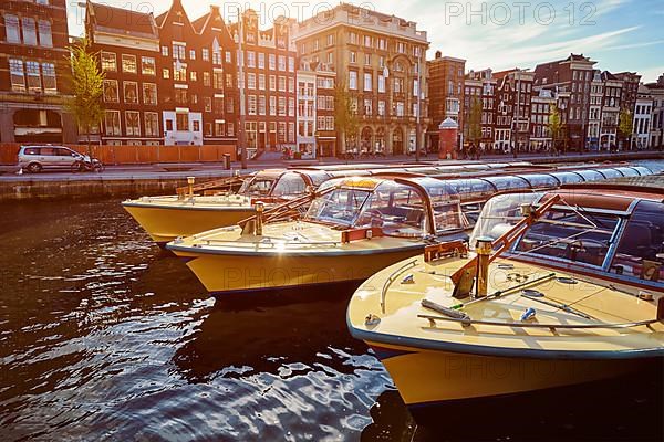 Amsterdam tourist boats in canal on sunset. Amsterdam