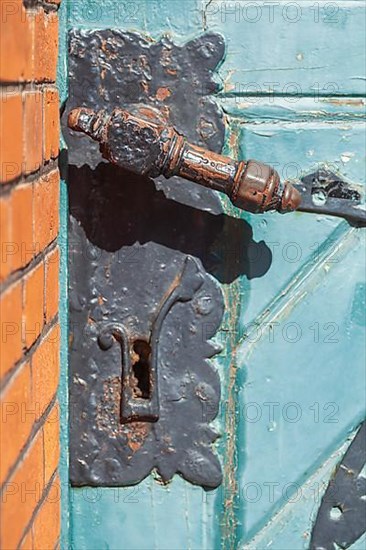 Old door lock with door handle on an old green wooden door