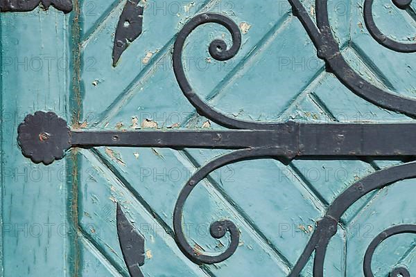 Old decorated iron door fitting on an old green wooden door