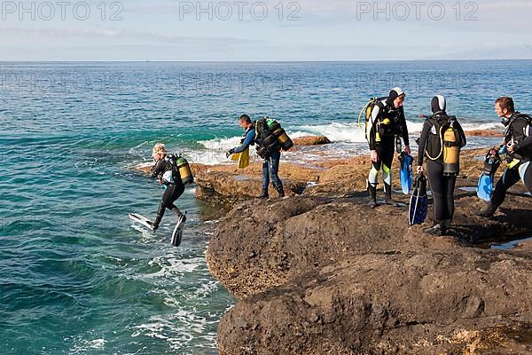 Diver entering sea from rocky coast