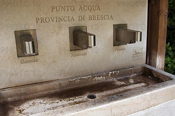 Public marble fountain with three taps in the village of Gargnano on the western shore of Lake Garda