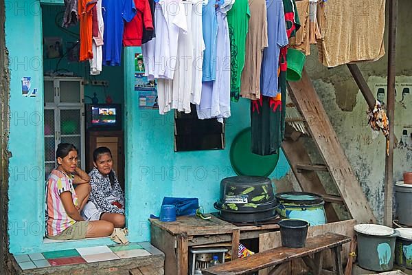 Indonesian mother and daughter at home with laundry drying on clothesline in Kota