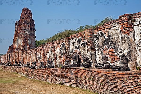Ruin of a Buddhist stupa with a row of broken Buddha statues at Wat Mahathat in Ayutthaya Historical Park