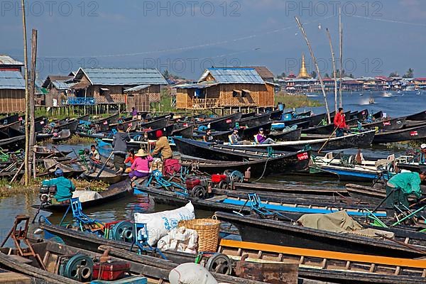 Open boats in lakeside village with traditional wooden houses on stilts in Inle Lake