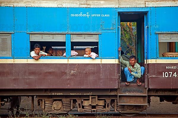 Burmese passengers in the blue upper class car of an old British train in Myanmar