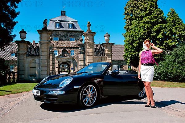 Woman with Porsche 911 cabriolet in front of castle