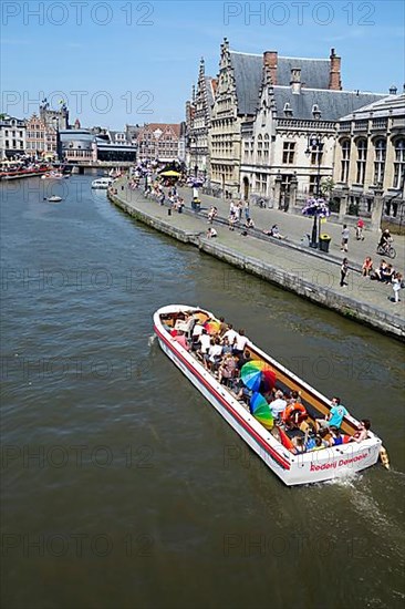 Sightseeing boat with tourists on the river Lys with a view of the guild houses on Graslei