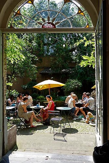 Tourists on a cosy terrace in the courtyard of a restaurant/cafe in Ghent