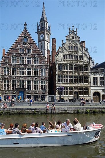 Sightseeing boat with tourists on the river Lys with a view of the guild houses on Graslei