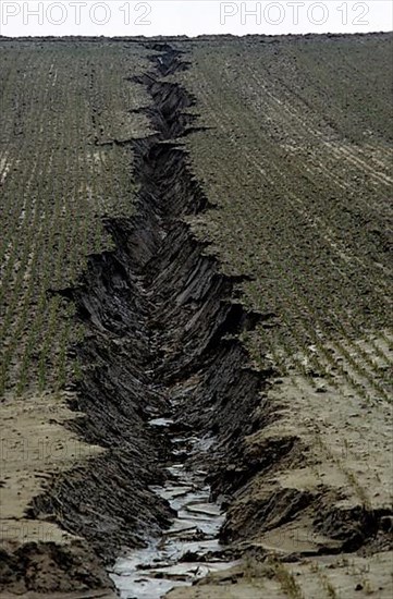 Gully in the field caused by erosion of farmland due to heavy rainfall washing away the soil