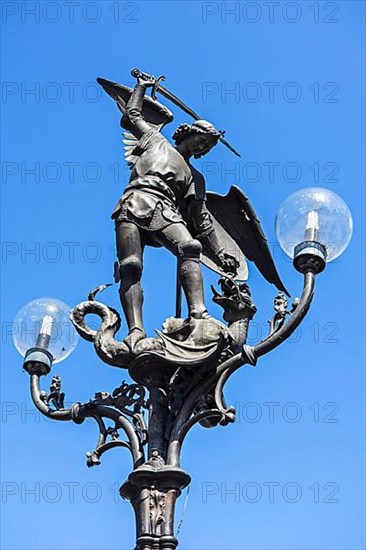 Lantern post with statue of Archangel Michael slaying Satan as a dragon at Saint Michael's Bridge in Ghent