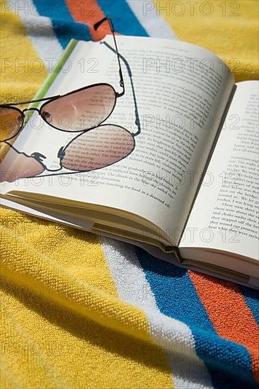Open book and sunglasses on beach towel
