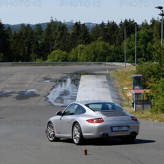 Porsche 911 997 Carrera sports car takes off to retain control during slalom course at driving safety training