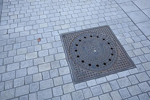 Square manhole cover with city coat of arms and a leaf on the market square in Tauberbischofsheim Baden-Wuerttemberg