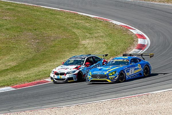 BMW M235i Racing is overtaken on the outside by Mercedes-AMG GT3 at 24h Nuerburgring race track 24-hour race