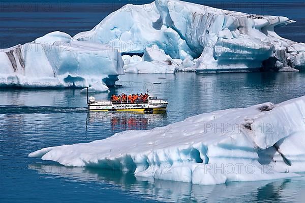 Tourists in an amphibious vehicle between icebergs