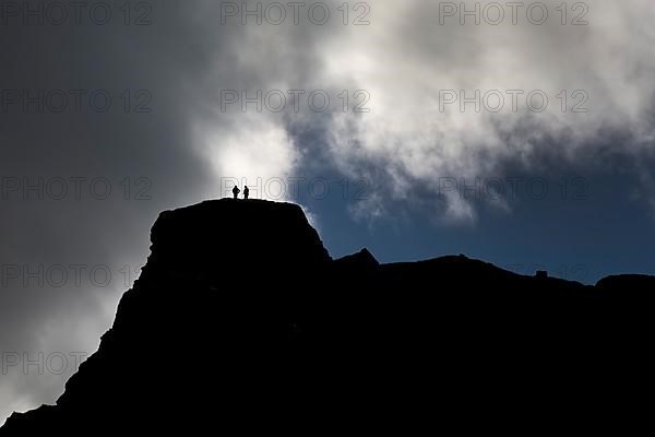 Dramatic sky with two people in front of clouds on a mountain in Kirkjubaejarklaustur