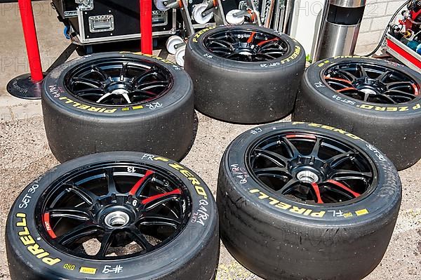 Used Pirelli racing tyres slicks on rim with central lock lie on ground in front of pit lane after tyre change during car race