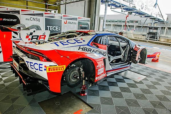 Racing car Lamborghini Huracan GT3 with wheels dismounted without tyres with visible brake disc stands in pit of pit lane at Nuerburgring race track