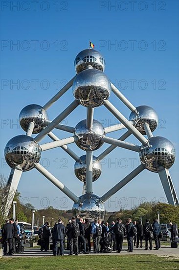 Businessmen in black suits wait in front of the Atomium
