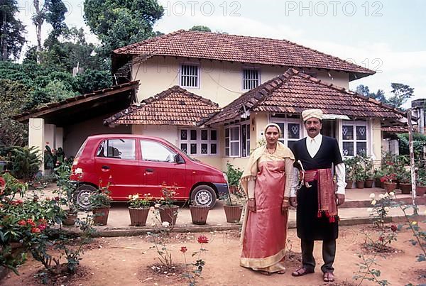 Kodava couple in traditional house in front of their house