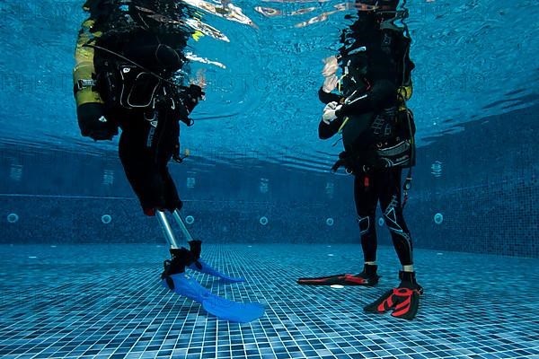 Disabled diver with prosthetic legs and diving instructor
