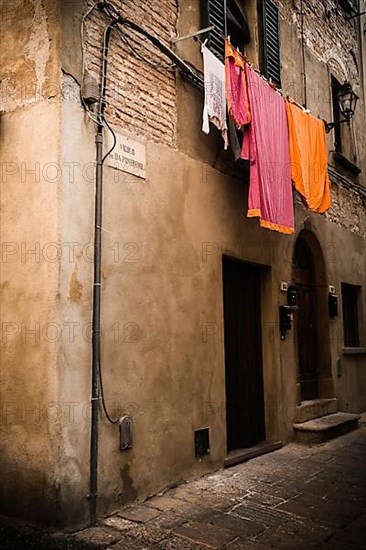 Laundry hanging along a narrow cobblestone street
