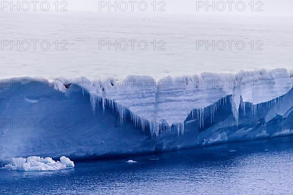 Icicles hanging from the ice wall of the melting Brasvellbreen glacier flowing into the Arctic Ocean