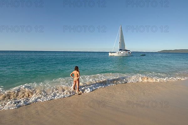 Woman on the beach watching sailboat