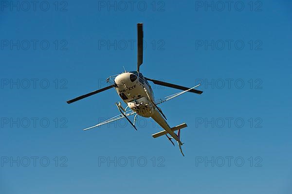 Helicopter Eurocopter AS350 B2 Ecureuil of Air-Glaciers SA with mounted spraying rods in flight