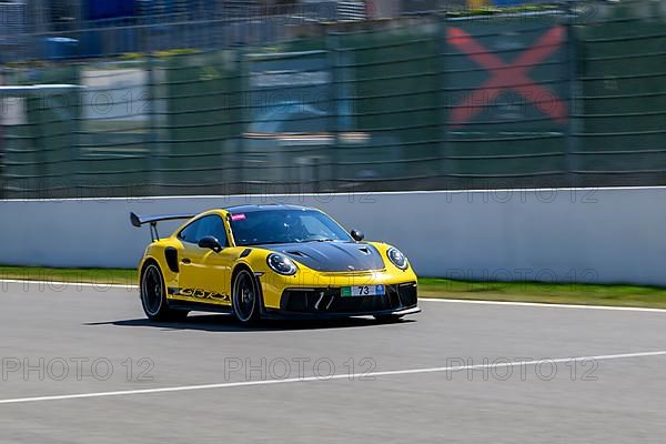 Yellow racing car sports car Porsche 911 GT3 RS races at high speed top speed during trackday on start-finish straight start-finish of race track